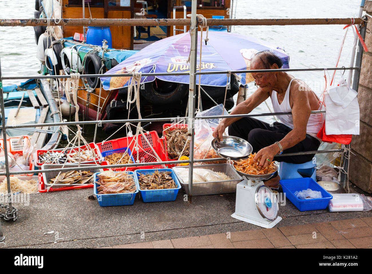 HONG KONG - JULY 13, 2017: A fisherman sells dried seafood along the pier at the Sai Kung floating seafood market in Hong Kong. Stock Photo