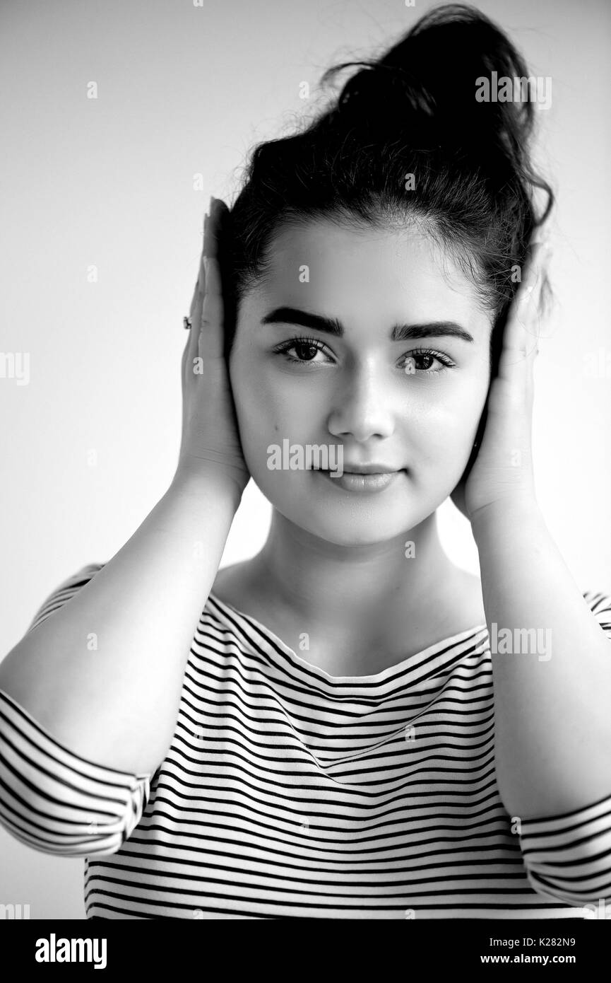 Emotions. Close-up facial portrait.Hear no evil. Girl on a light background covers his ears, , black and white Stock Photo