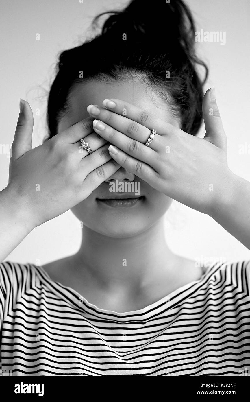 Emotions. Close-up facial portrait. See no evil.Girl on a light background closes his eyes, black and white Stock Photo