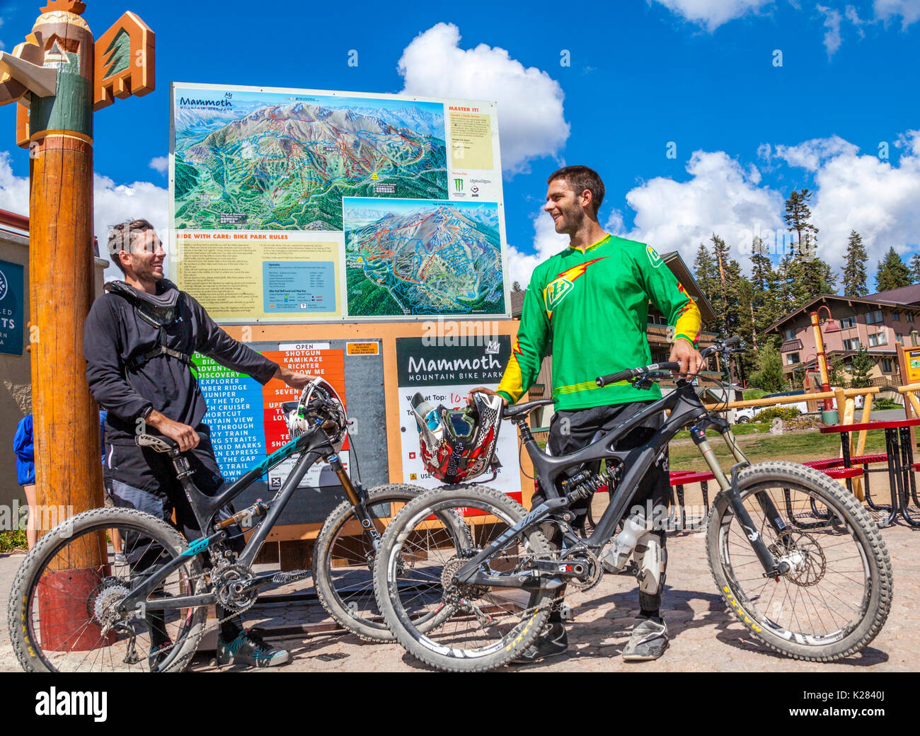 Friends with mountain bikes near sign with trail map by the Adventure Center at Mammoth Mountain in Mammoth Lakes, California Stock Photo