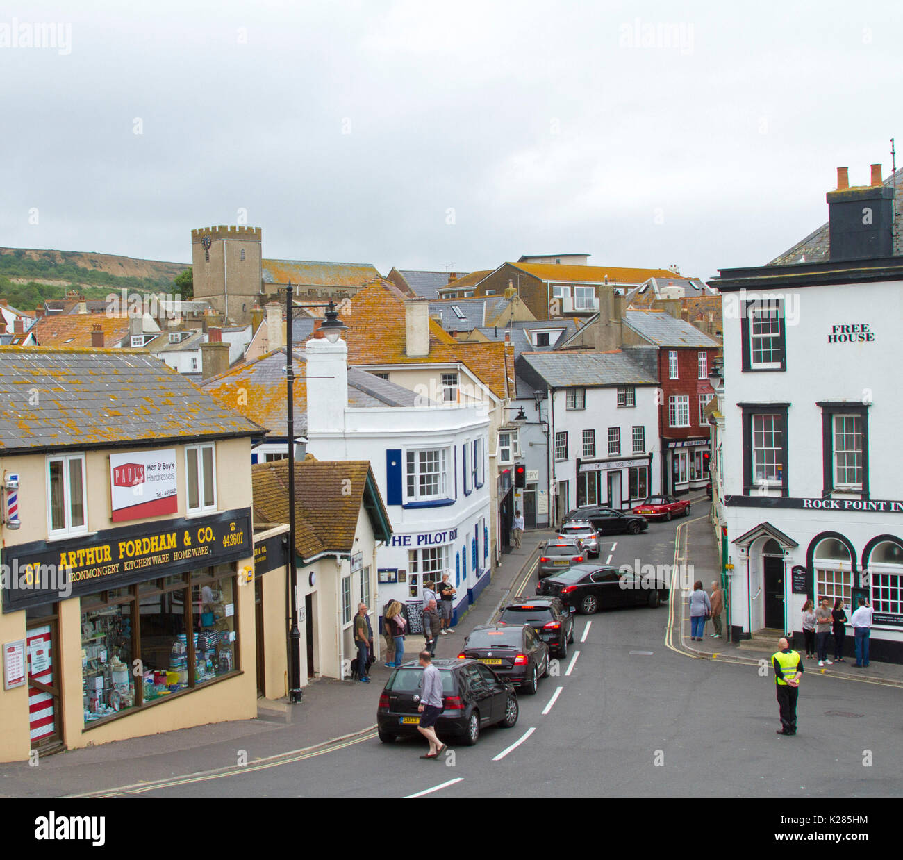 Traffic congestion with row of cars at red traffic lights in narrow street between high buildings in Lyme Regis, West Dorset, England Stock Photo