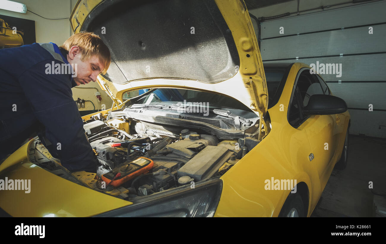 Mechanic in car service repairing in engine compartment Stock Photo
