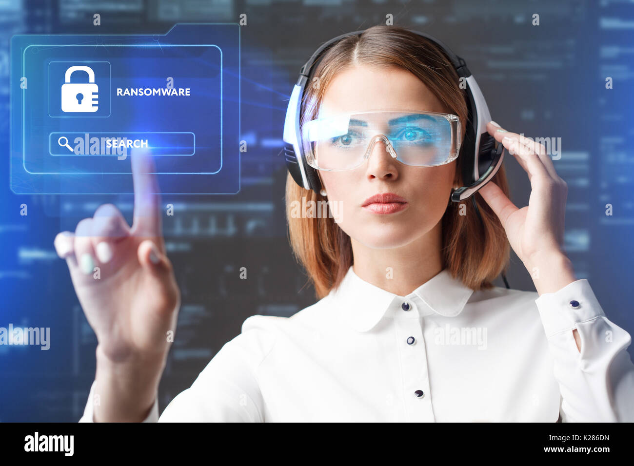 Business, Technology, Internet and network concept. Technology future. Young businesswoman working in virtual glasses, select the icon RANSOMWARE on t Stock Photo
