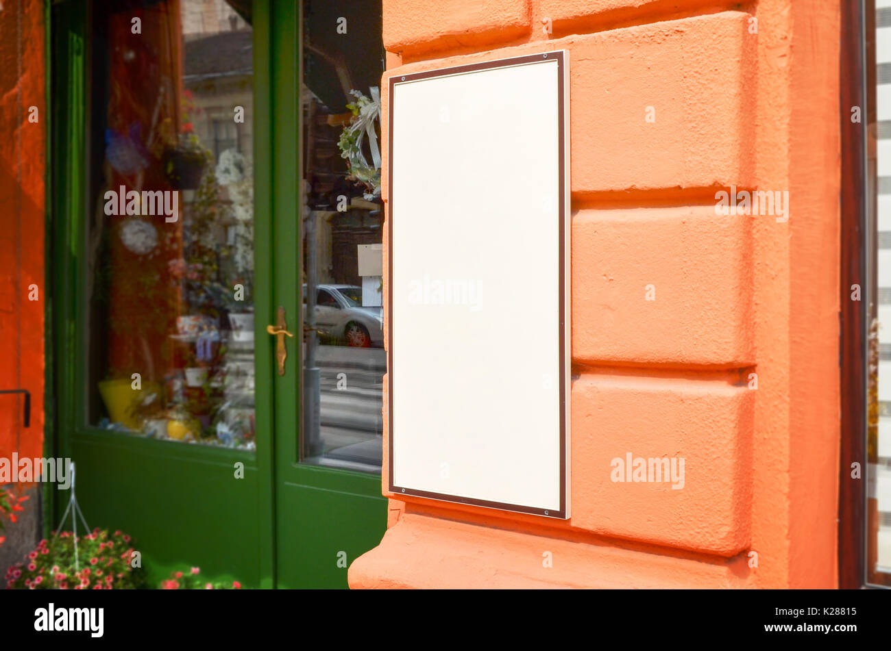 Signboard view of empty white mockup signage in frame with orange shop wall in background Stock Photo
