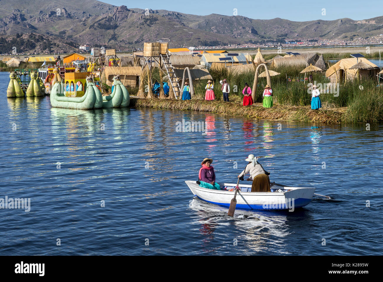 Uros floating Island made from totora reed with Puno in background Lake Titicaca Peru Stock Photo