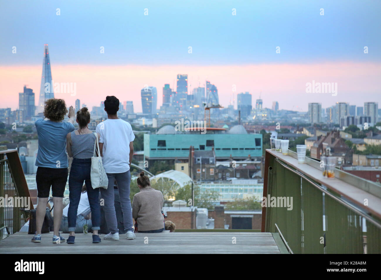 Young people view the London skyline at dusk from Frank's Café, the famous roof-top bar and restaurant on the multi-storey car park in Peckham, UK. Stock Photo