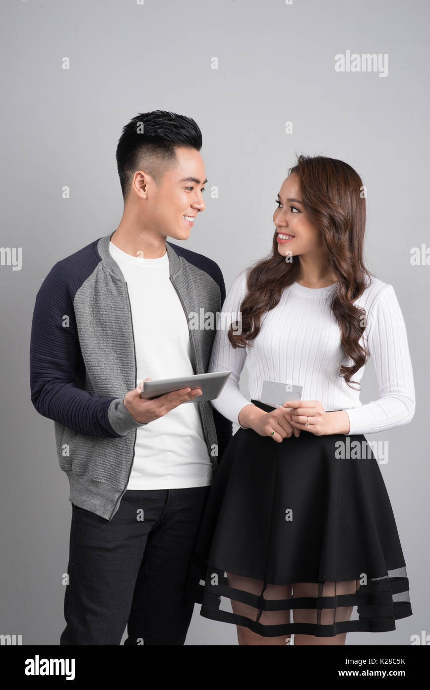 Couple with digital tablet and credit card in studio isolated gray background Stock Photo