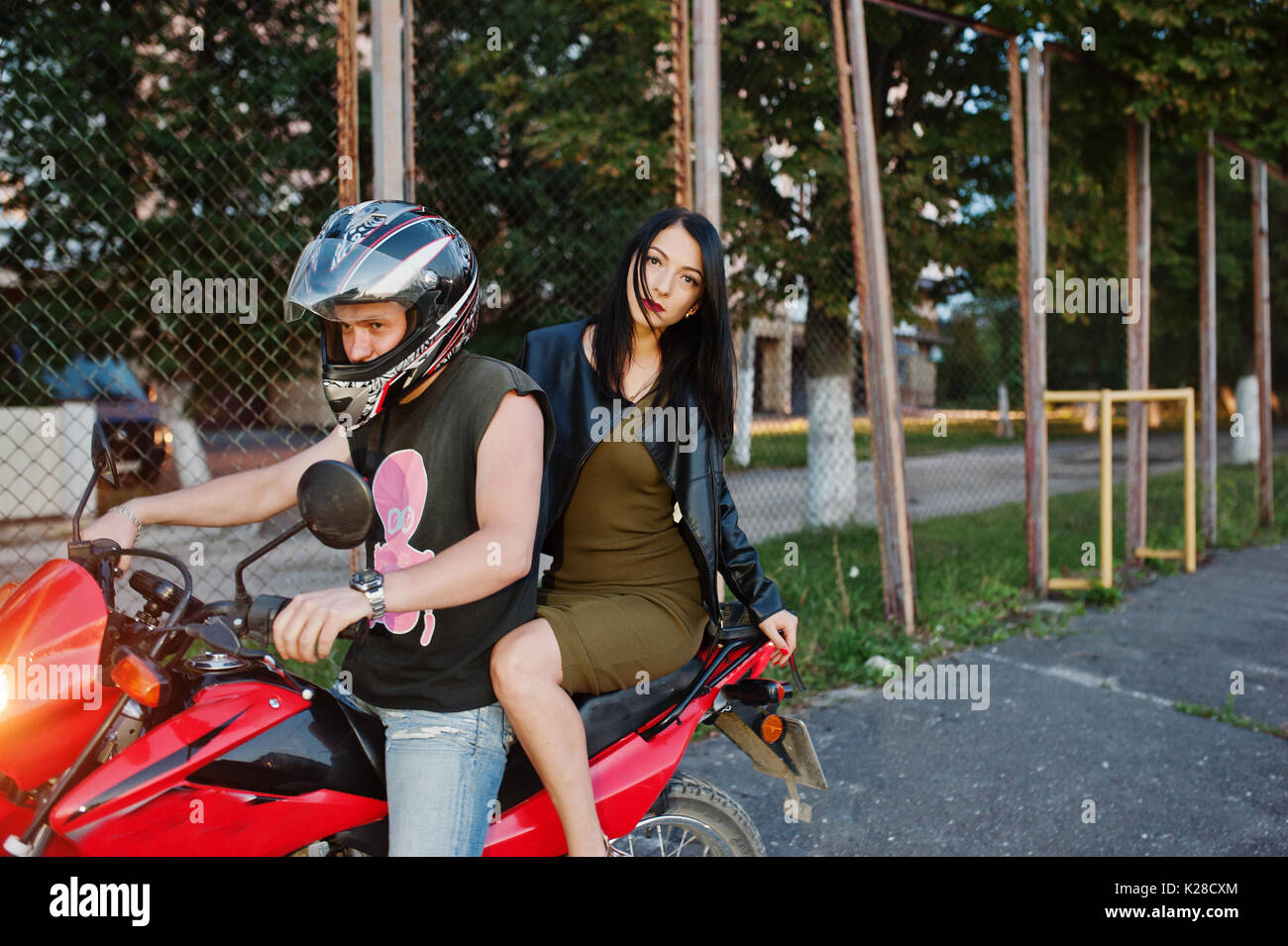 Woman in dress and leather jacket riding a motorbike with another man Stock Photo Alamy