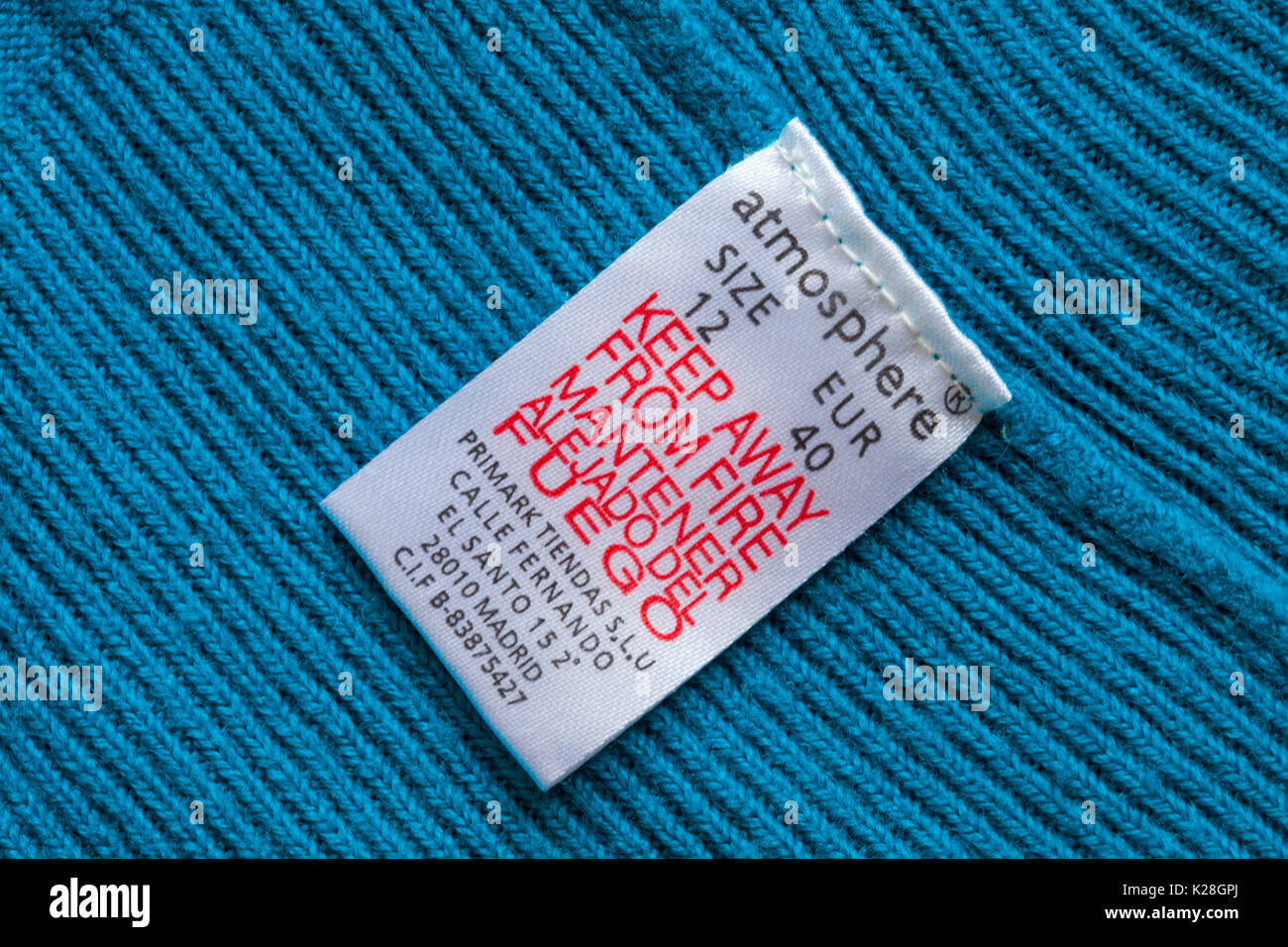 Keep away from fire label in blue atmosphere jumper from Primark size 12 - in English and Spanish Stock Photo