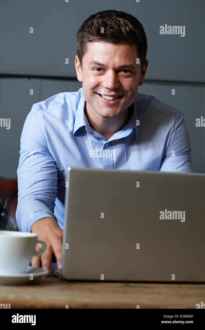 Businessman Working On Laptop In Internet Cafe Stock Photo