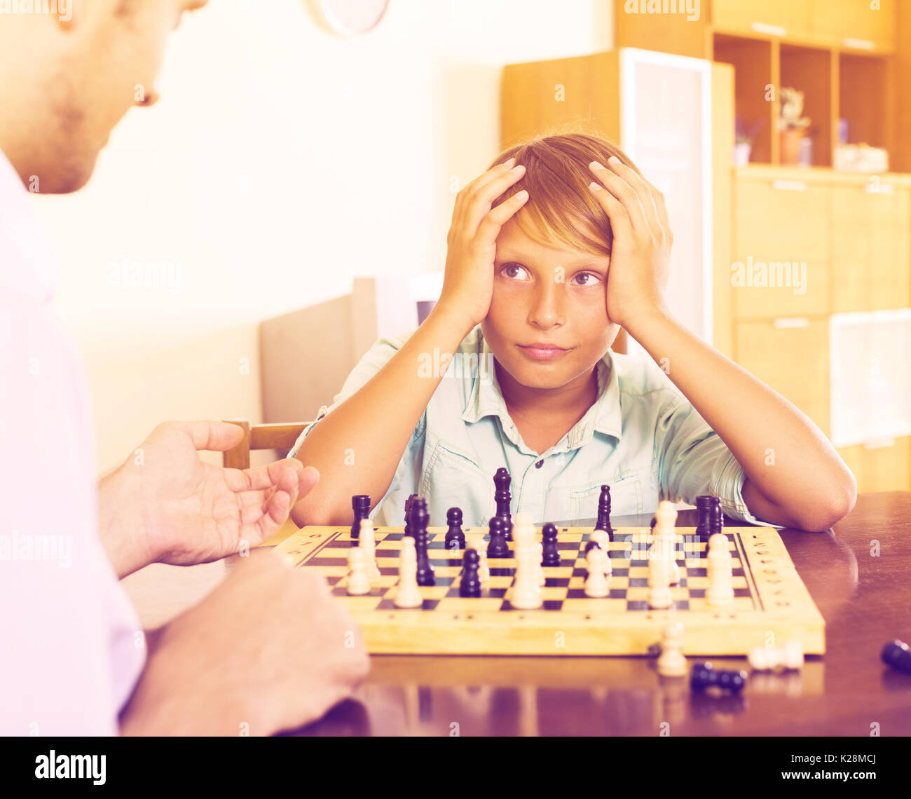 Father and son playing chess at home, boy losing Stock Photo