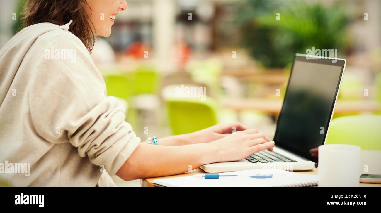 Side view of student using laptop at cafeteria table Stock Photo