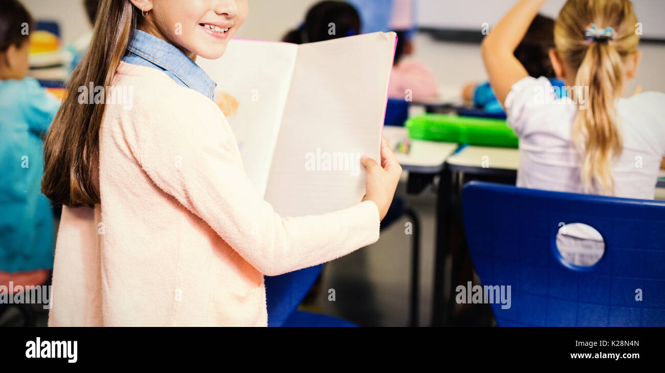 Portrait of schoolgirl standing with book in classroom Stock Photo - Alamy
