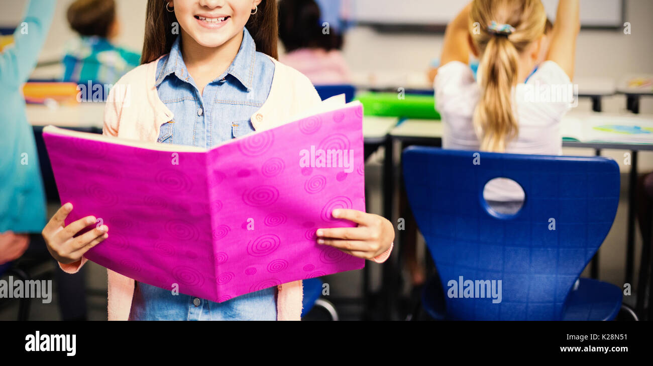 Portrait of schoolgirl with book standing in classroom Stock Photo - Alamy
