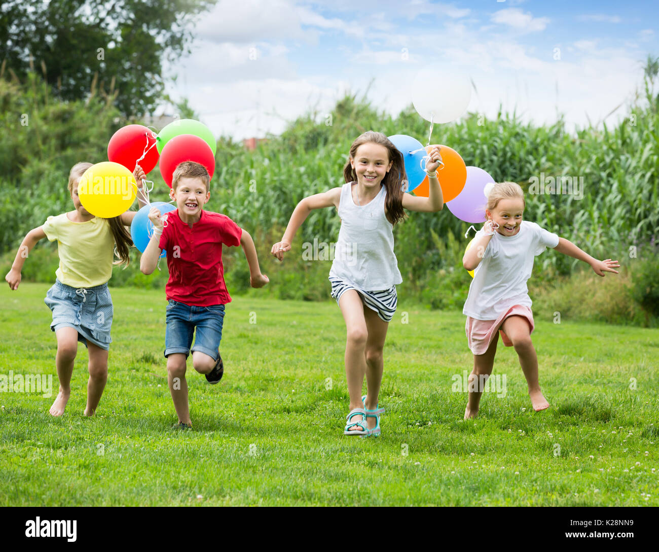 Four Glad Kids Happily Playing And Running Together On Green Lawn Stock  Photo, Picture and Royalty Free Image. Image 74181270.