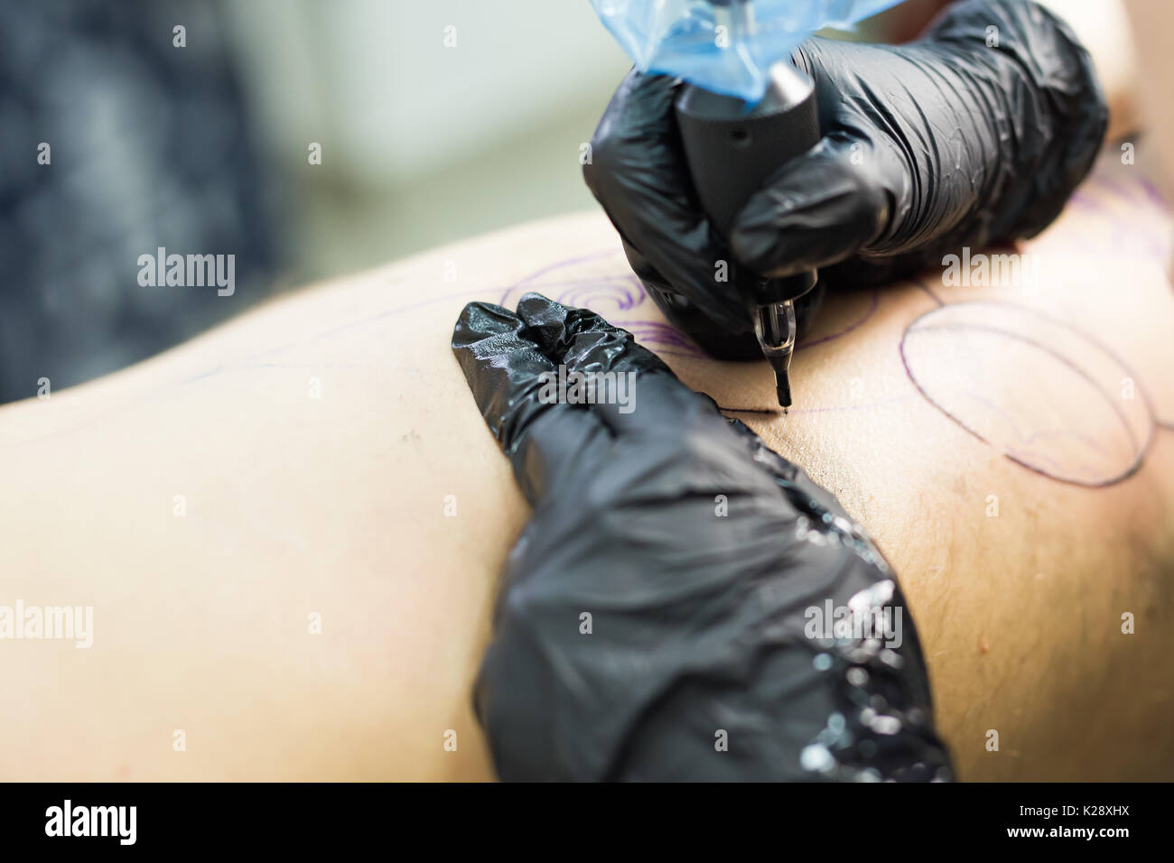 Professional tattooer make the tattoo with gloves on by special tool close up. Stock Photo
