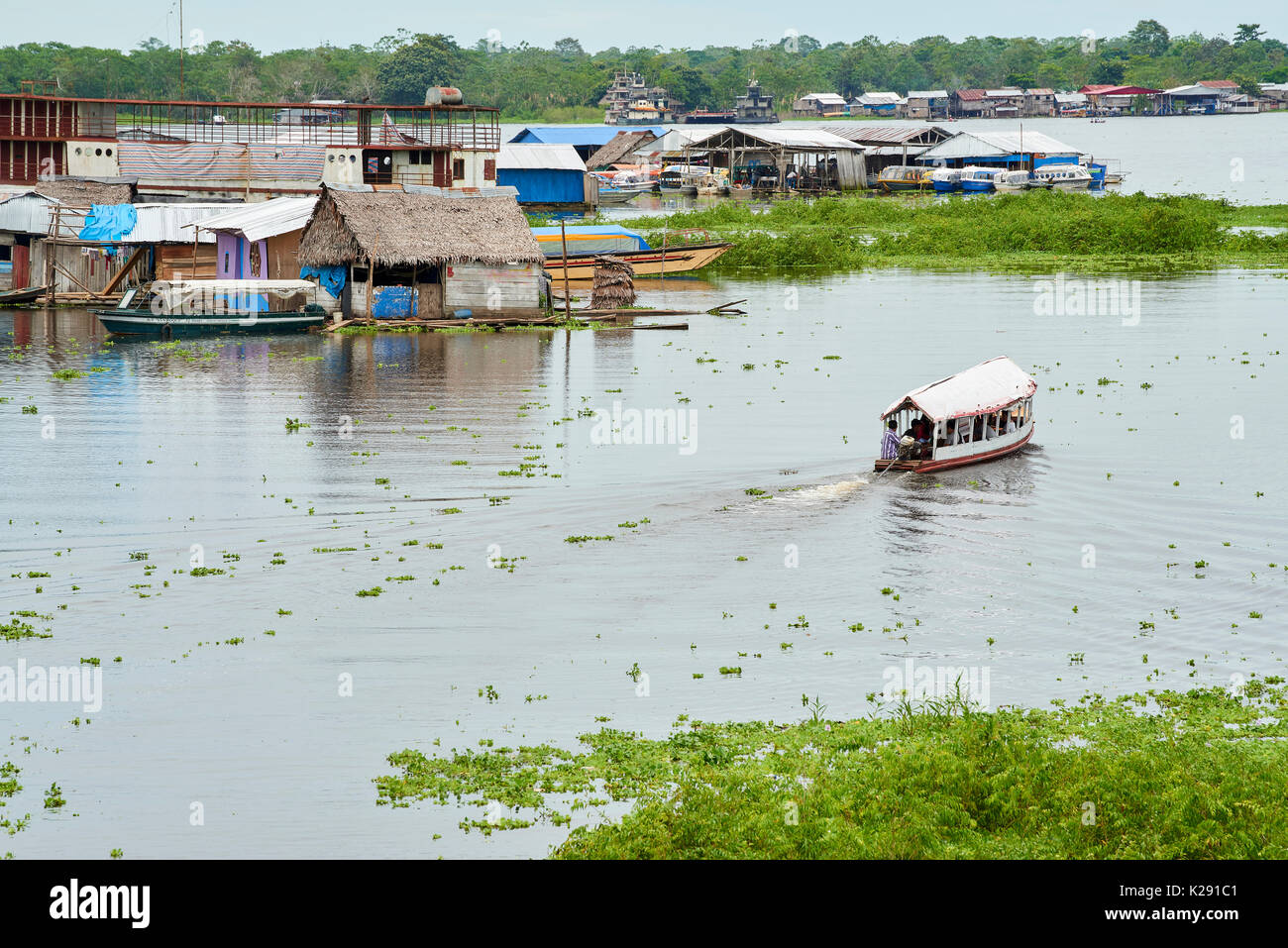 Riverboat in Nanay River with floating houses in the background. Iquitos, Peru. Stock Photo