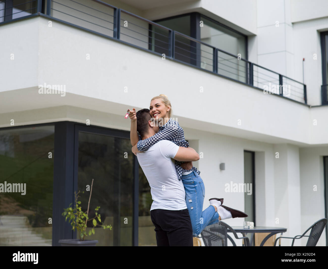 Portrait of a happy young couple hugging in front of their new luxury ...