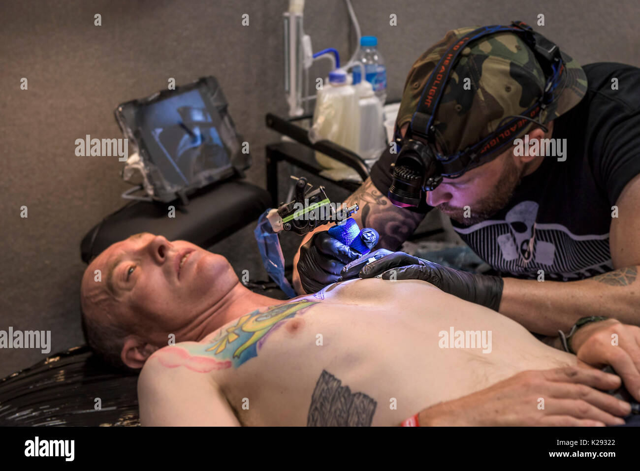 Cornwall Tattoo Convention - a tattoist tattooing the chest of a customer at the Cornwall tattoo Convention. Stock Photo