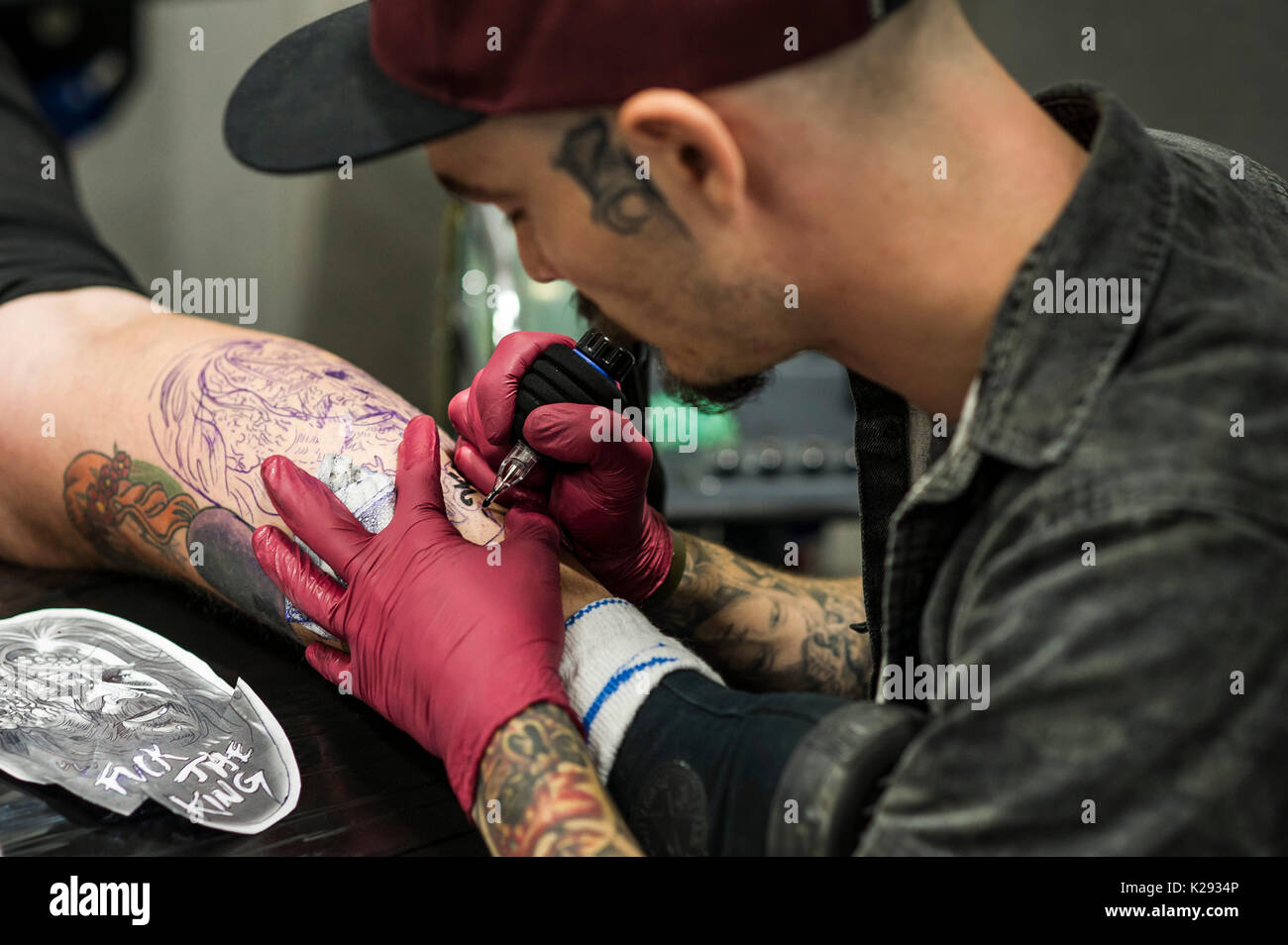 Cornwall Tattoo Convention -  a closeup view of Josh Docksey tattooing the leg of a customer at the Cornwall Tattoo Convention. Stock Photo