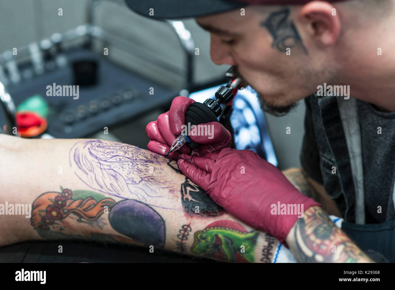 Tattooing. A closeup view of tattooist Josh Docksey tattooing the leg of a customer at the Cornwall Tattoo Convention. Stock Photo