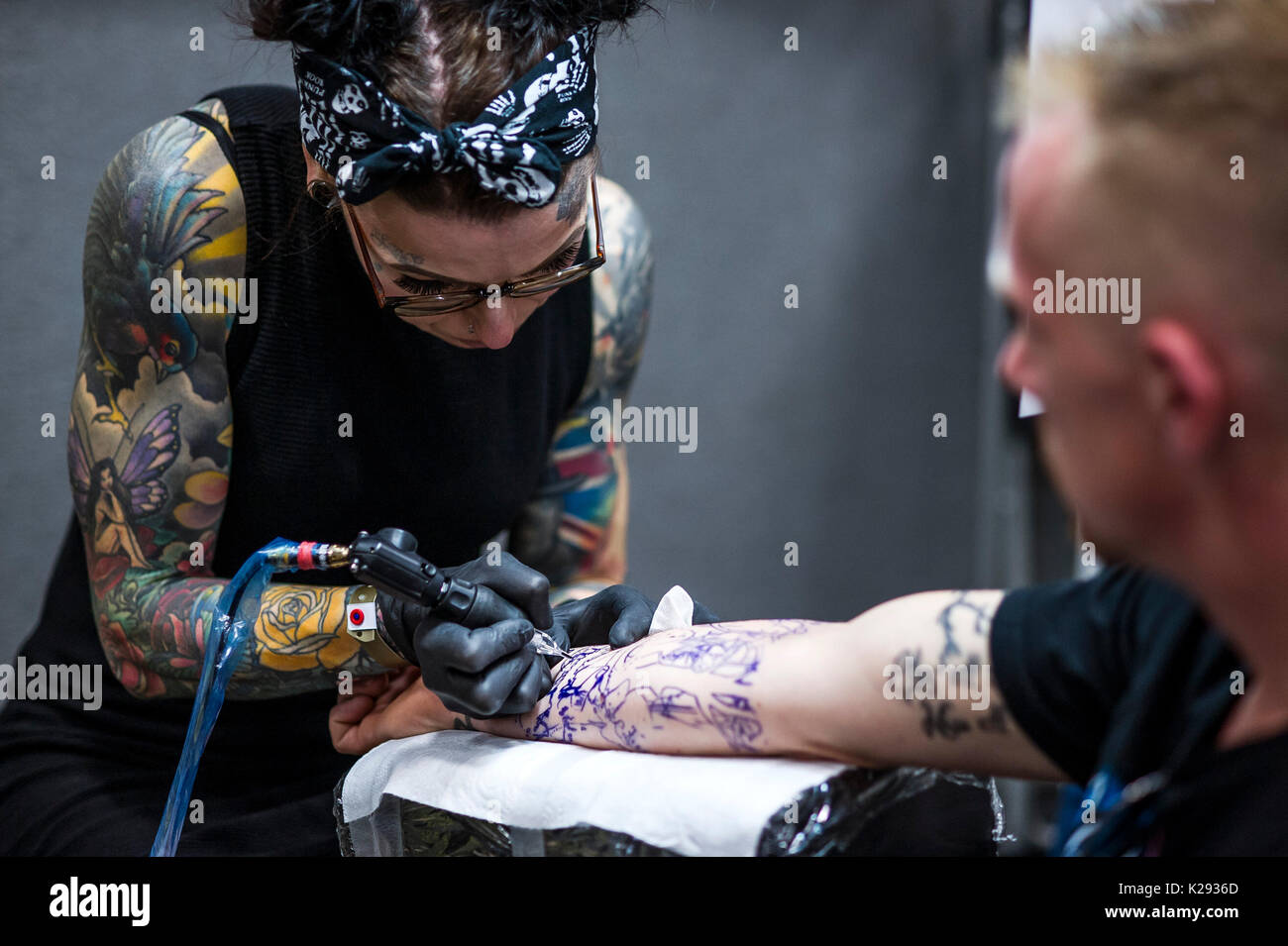 Tattooing. A female tattooist applying a tattoo to the forearm of a customer at the Cornwall tattoo Convention. Stock Photo