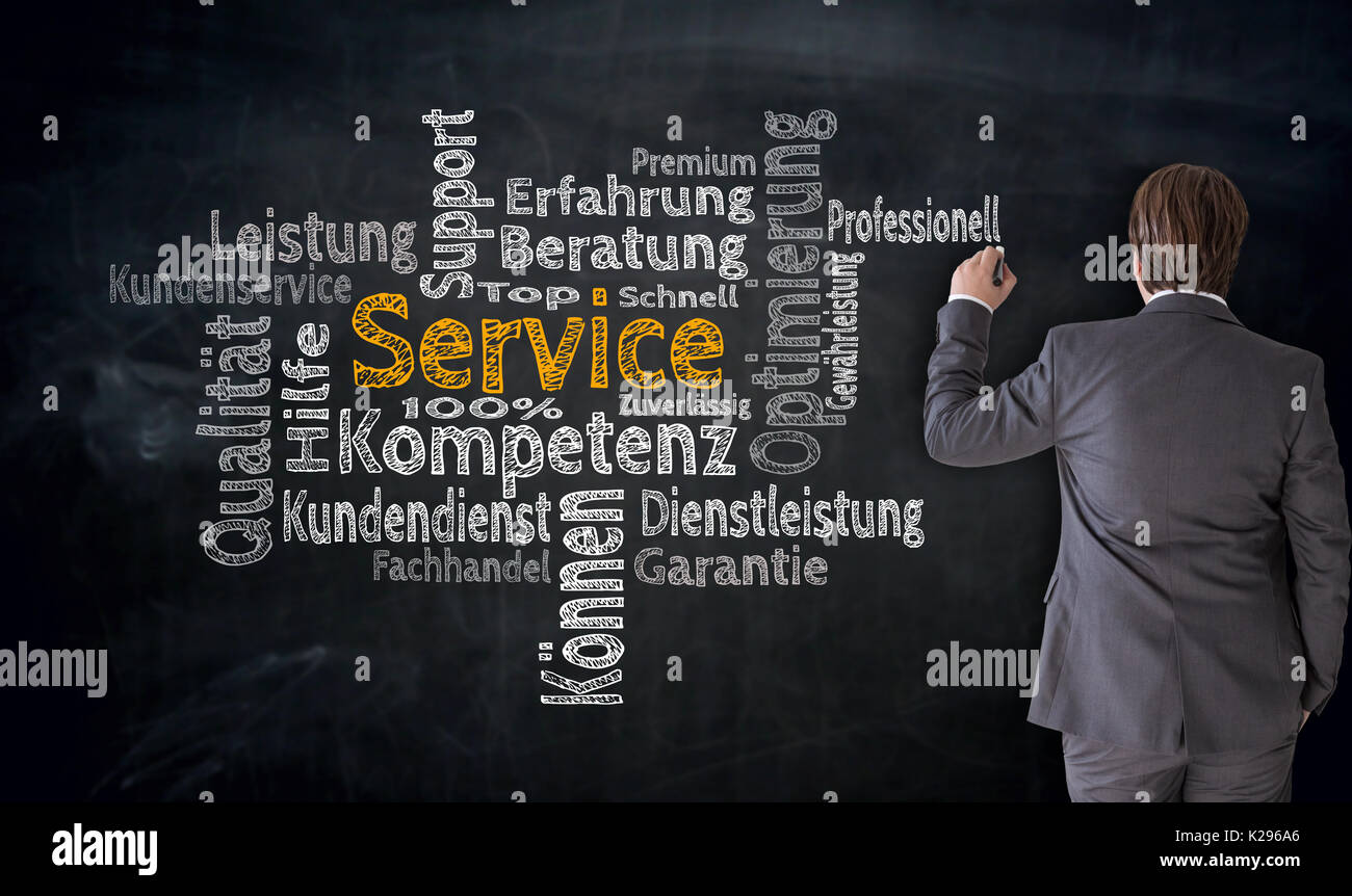 Businessman writes service (in german Competence, consulting) cloud on blackboard concept. Stock Photo