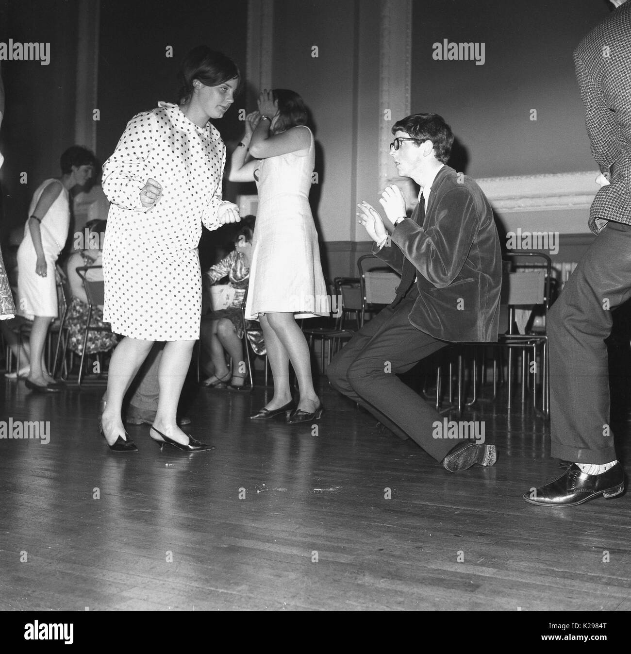 1964, historial, England, UK, the new dance craze, picture shows a boy and girl dancing solo to the new sounds of the era, with the boy really grooving, perhaps inspired by the hit sound, 'the twist,'. Stock Photo