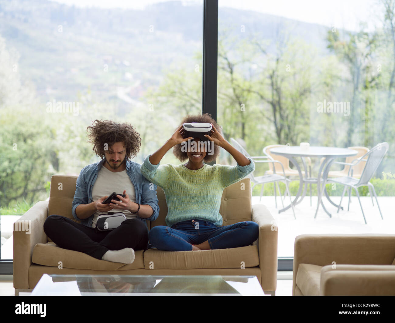 Multiethnic Couple using virtual reality headset in living room at home ...