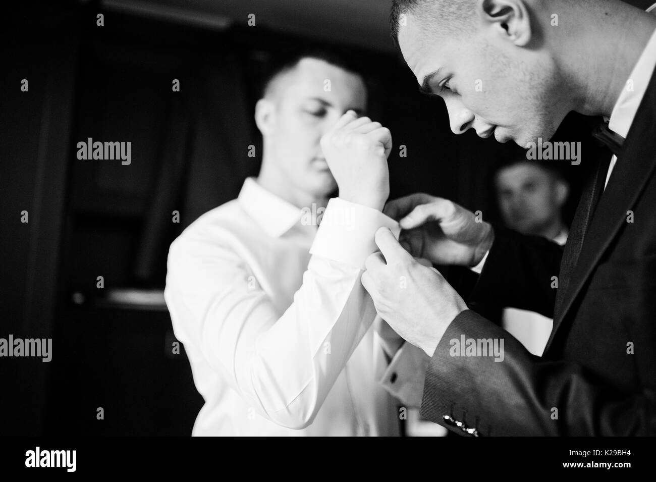 Groomsmen helping groom to dress up and get ready for his wedding ceremony. Black and white photo. Stock Photo