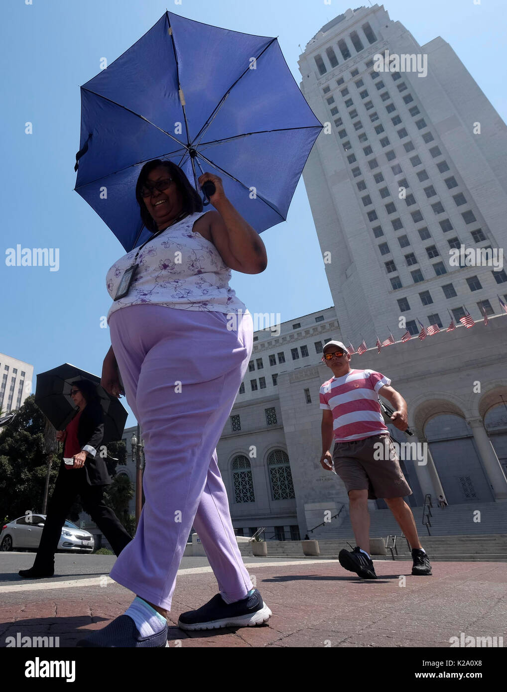 Los Angeles, USA. 29th Aug, 2017. A woman holds an umbrella to shield herself from the sun as she waits for a bus on Aug. 29, 2017 in Los Angeles, the United States. A heat wave hit south California on Tuesday, raising the highest temperature to more than 37 degrees Celsius in many areas. Credit: Zhao Hanrong/Xinhua/Alamy Live News Stock Photo