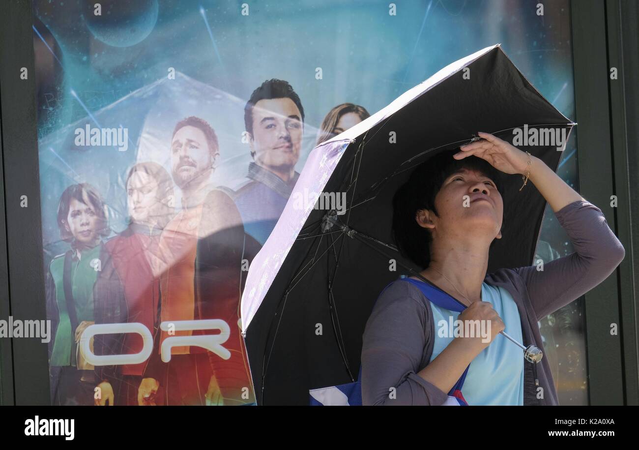 Los Angeles, USA. 29th Aug, 2017. A woman holds an umbrella to shield herself from the sun while waiting for a bus on Aug. 29, 2017 in Los Angeles, the United States. A heat wave hit south California on Tuesday, raising the highest temperature to more than 37 degrees Celsius in many areas. Credit: Zhao Hanrong/Xinhua/Alamy Live News Stock Photo