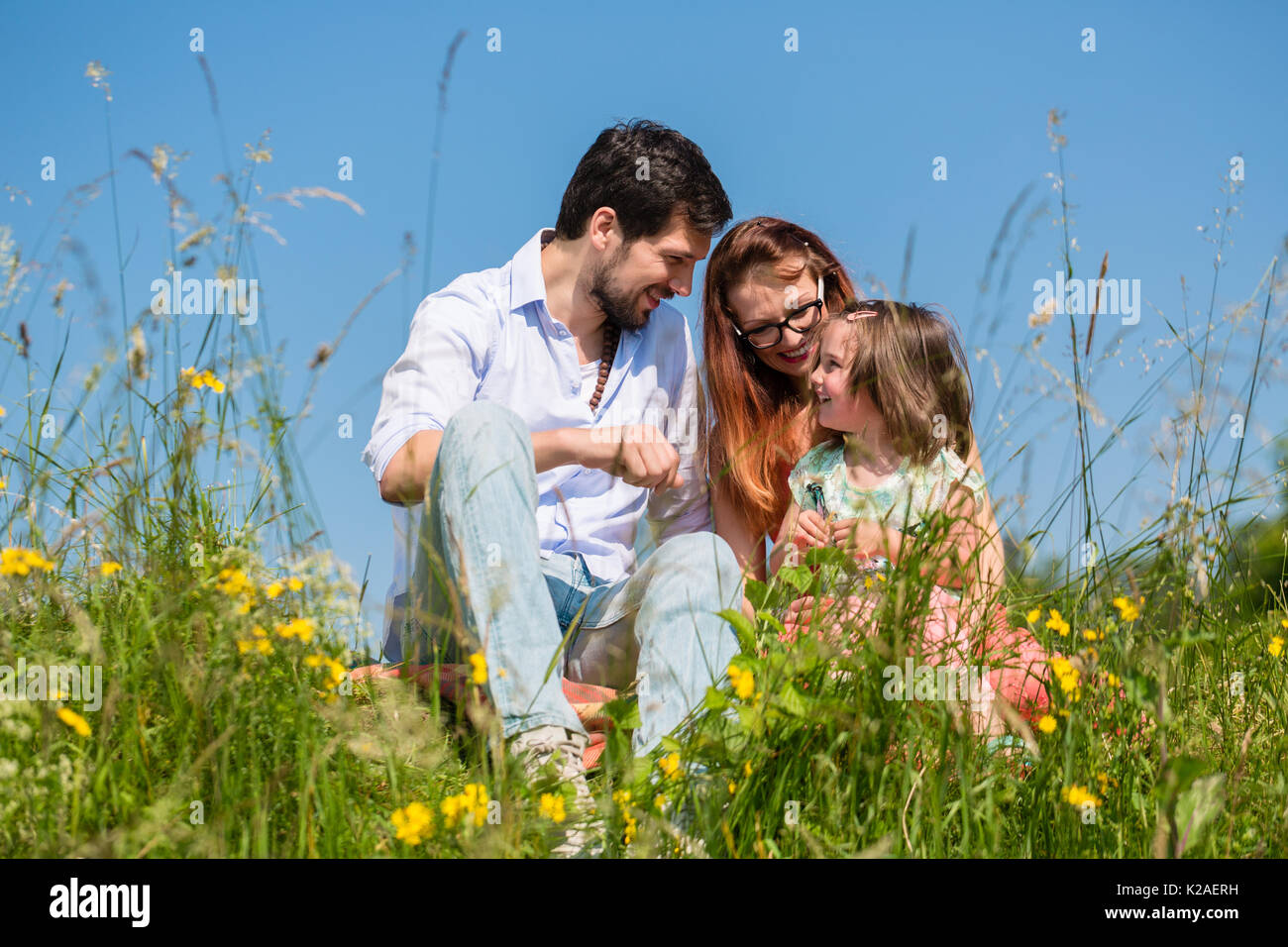 Family cuddling sitting on meadow Stock Photo