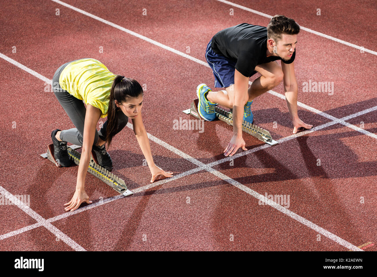 Male and female athlete in starting position at starting block o Stock Photo