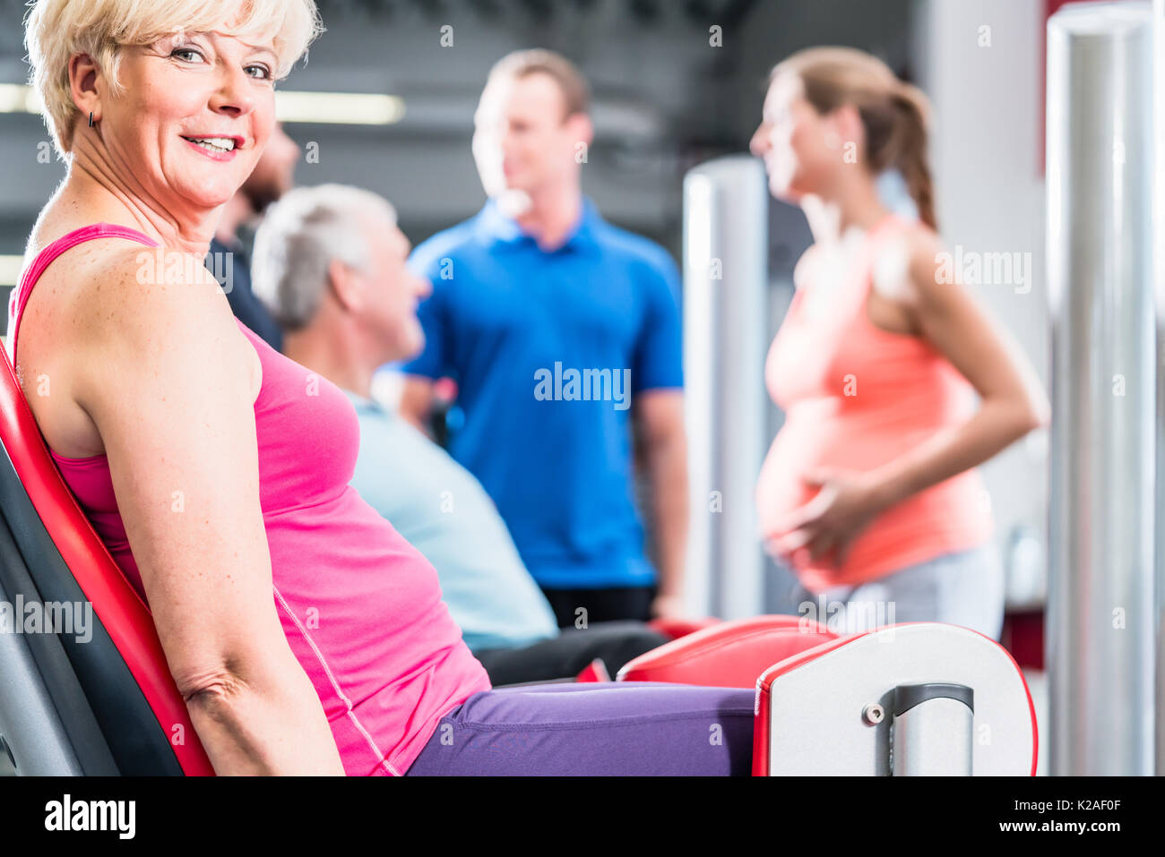 senior woman in group with pregnant woman working out at the gym Stock Photo