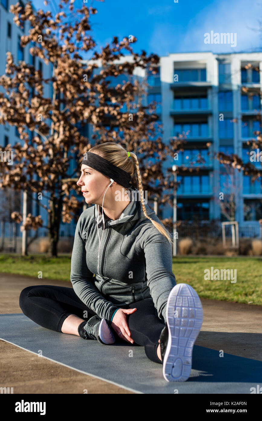 Fit young woman stretching her leg during outdoor warm-up exerci Stock Photo