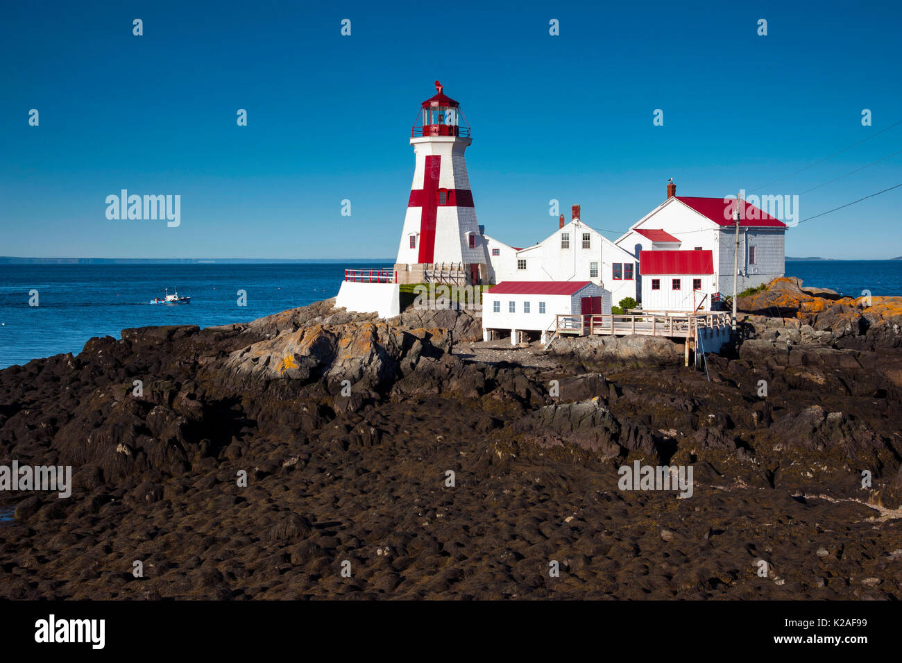 Head Harbor lighthouse guides fishing boat around the tip of Campobello Island during low tide in Canada. it has the lowest tides on the east coast. Stock Photo