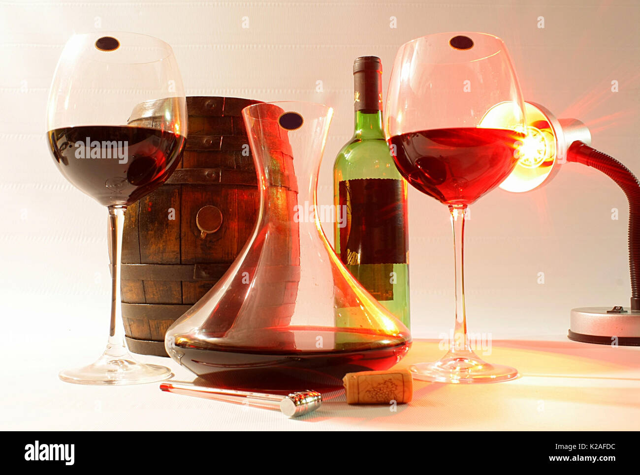 Glasses, decanter, bottle and barrel, lit by a lamp Stock Photo