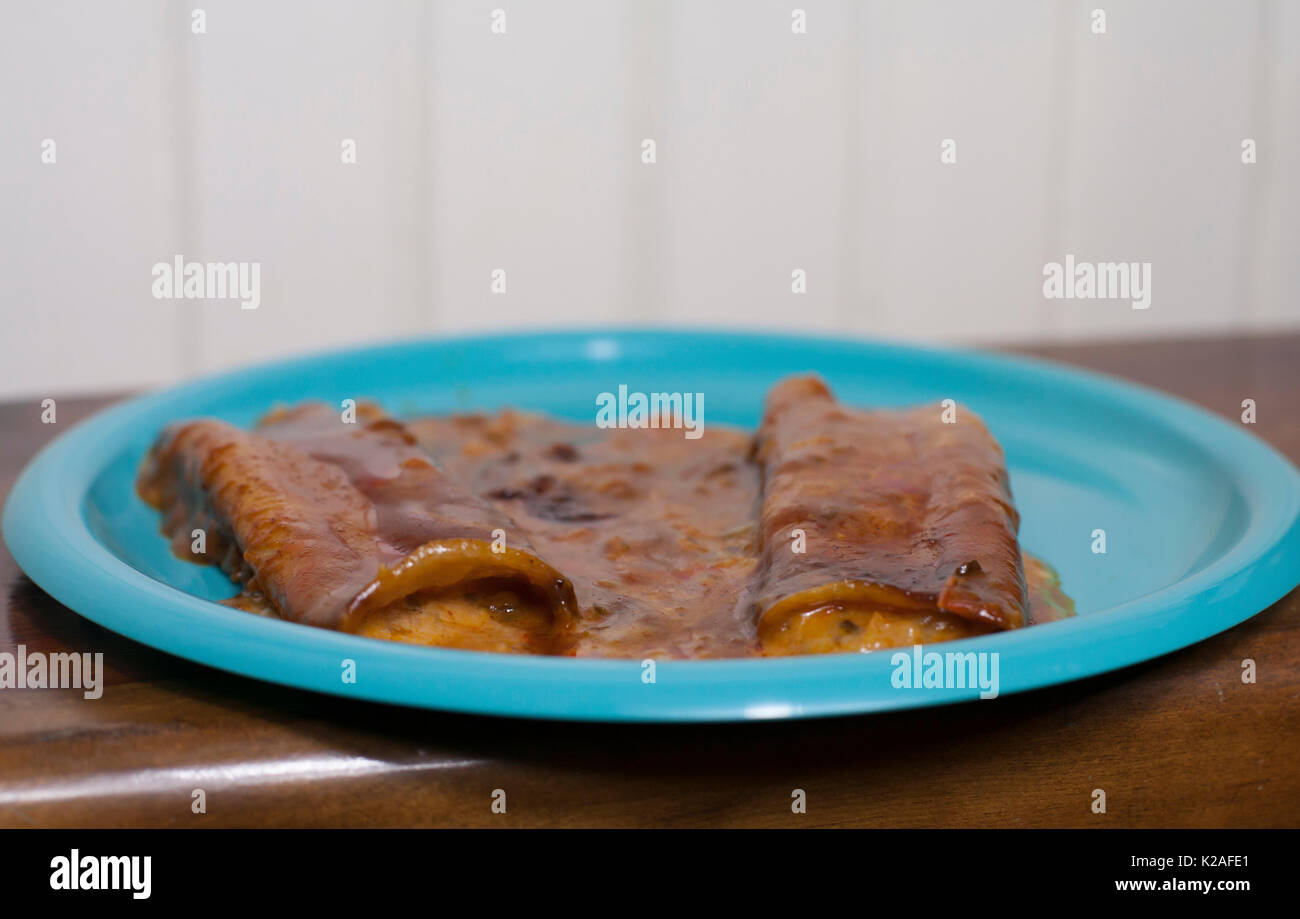 Close up of three cheese enchiladas on a pretty blue plate Stock Photo