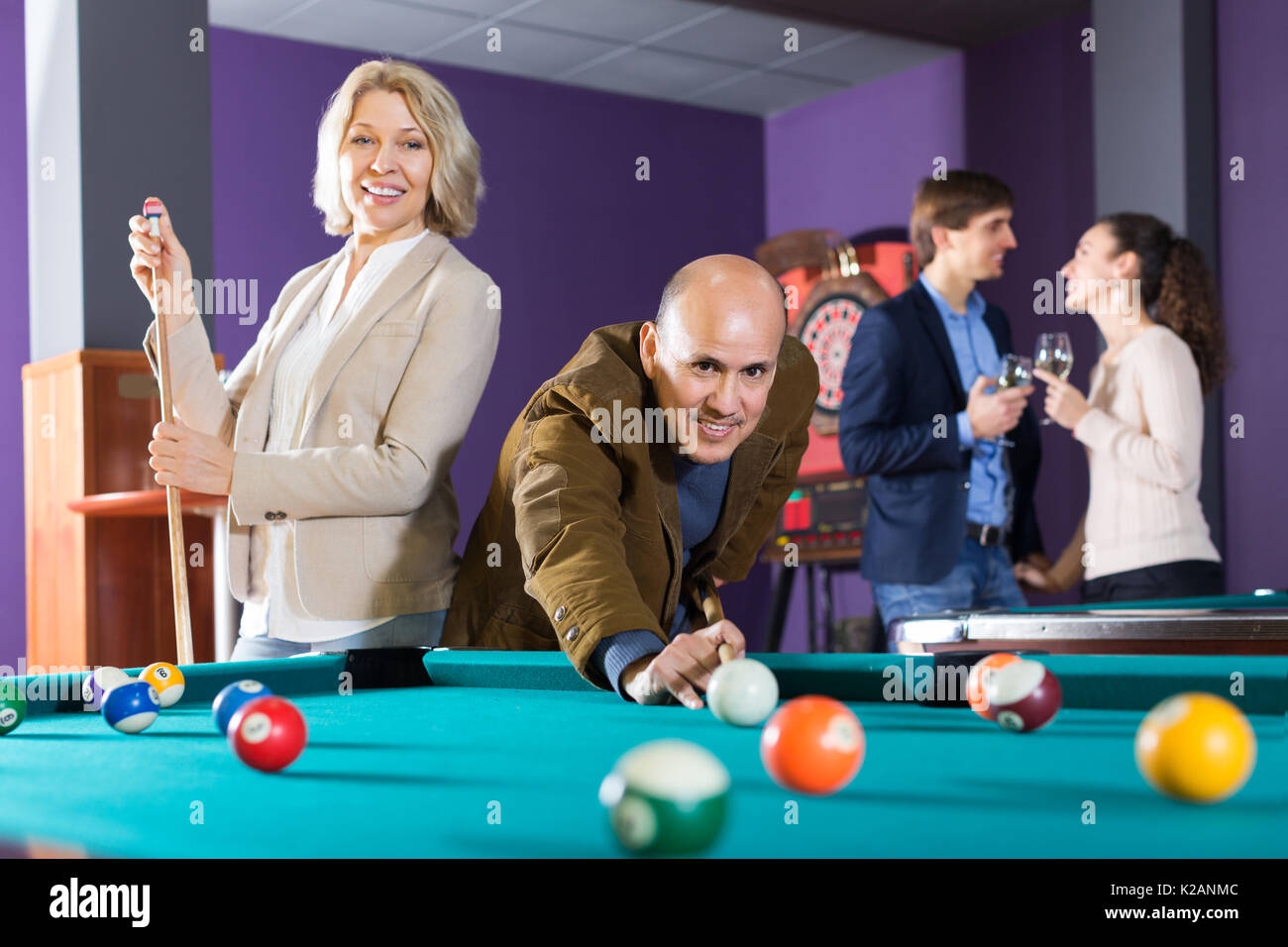 Positive people playing billiard and darts as hanging out Stock Photo