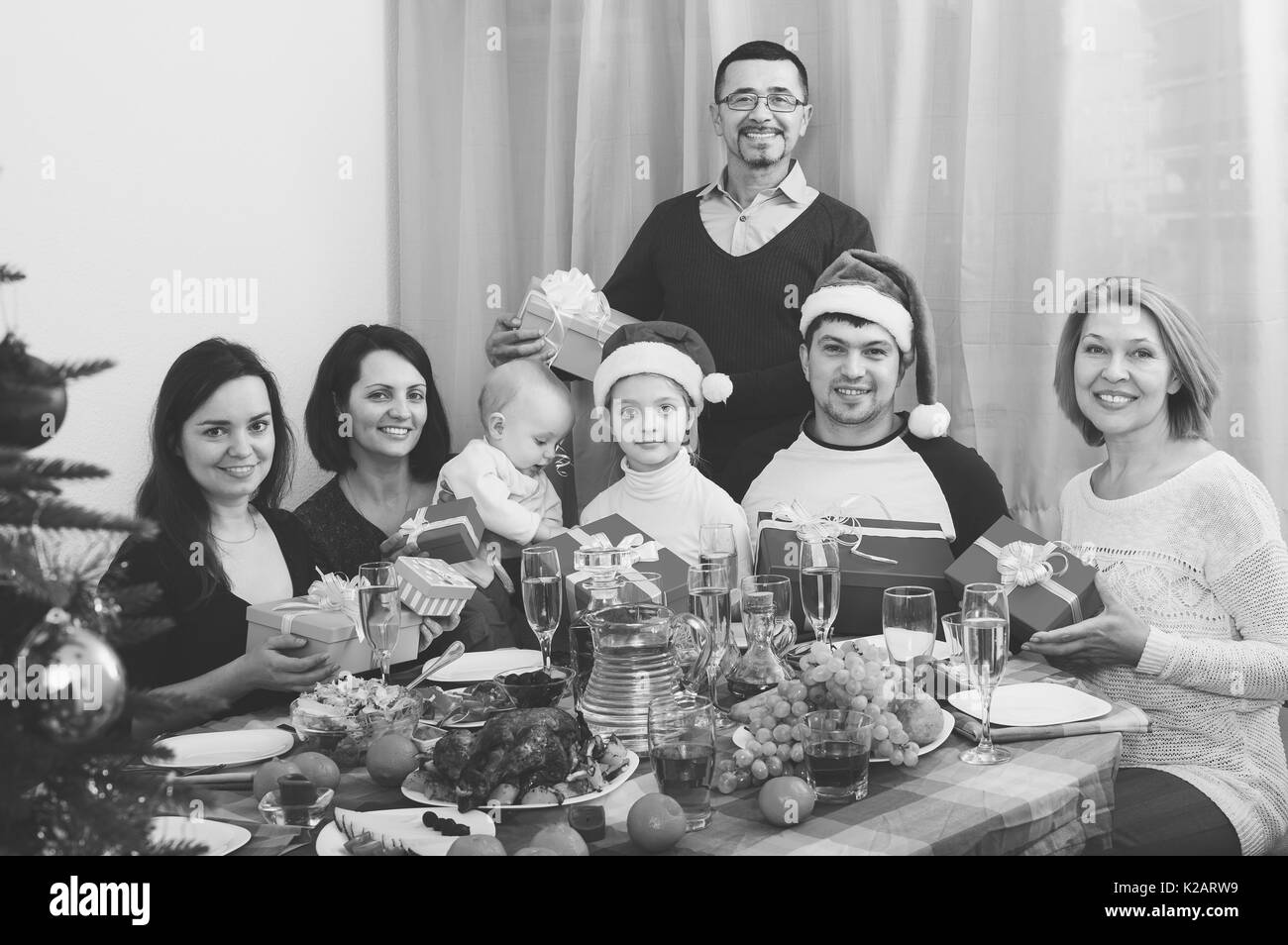 Portrait of big multigenerational family with gifts sitting at festive Xmas table. Focus on girl Stock Photo