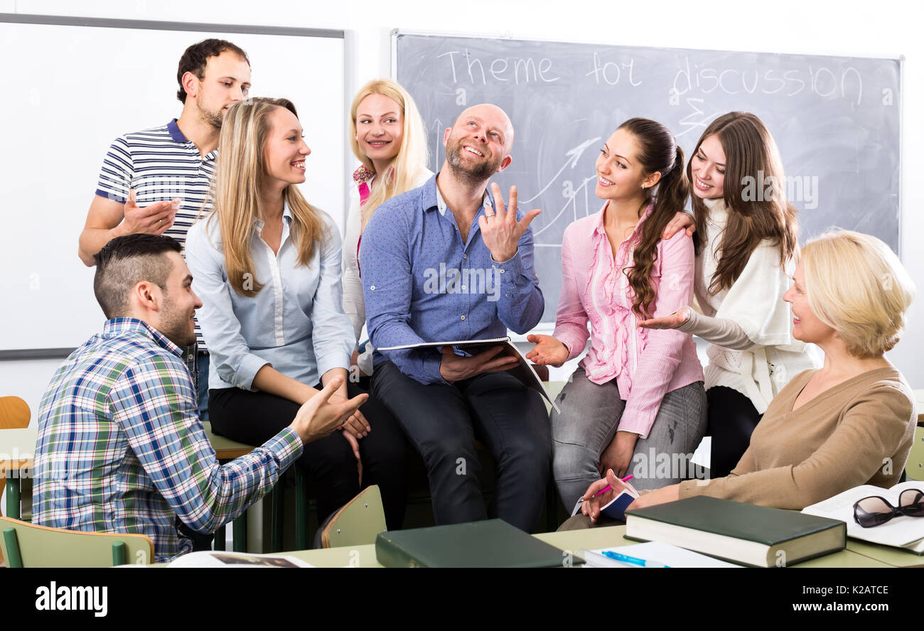 Highschool students in a classroom listening to stories of their charming teacher during a break Stock Photo