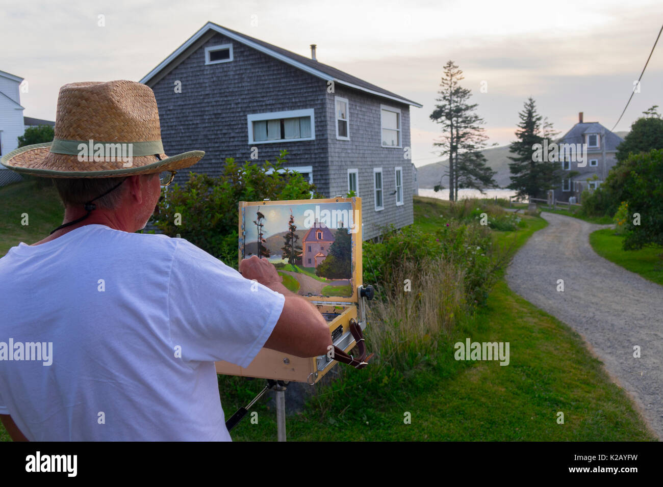 USA Maine ME Monhegan Island an artist is painting a home a gravel road at the end of the day Stock Photo