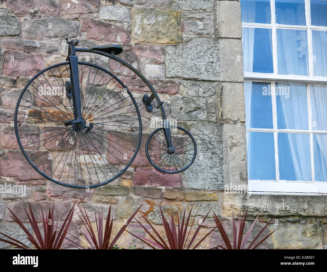 Old fashioned penny farthing bicycle model featured on stone wall of an old pub wall, Candlemaker Row, Edinburgh, Scotland, UK Stock Photo