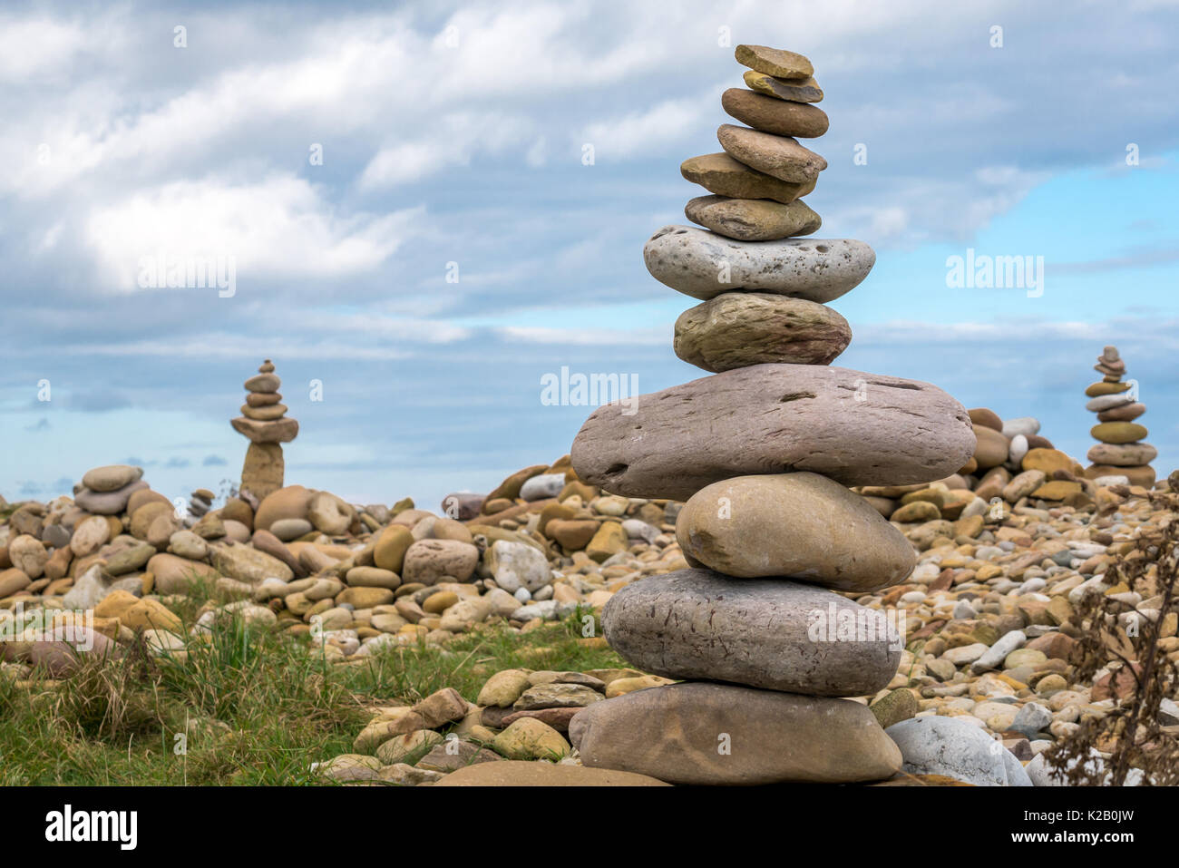 Stone balanced towers of pink and yellow stones, inukshuks or cairns, beach at Holy Island, Lindisfarne, Northumberland, England, UK Stock Photo