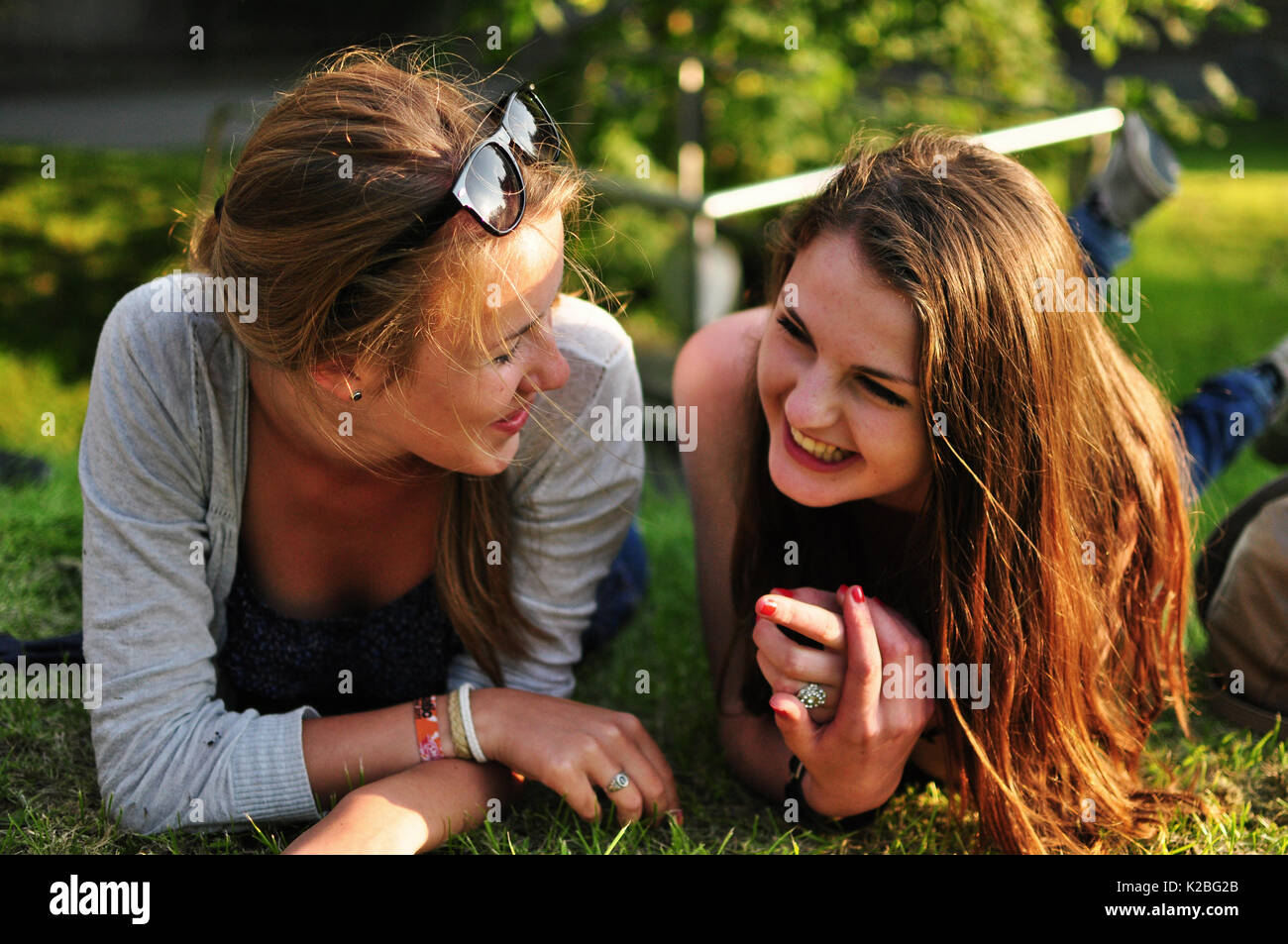 Two giggling friends lying on grass Stock Photo