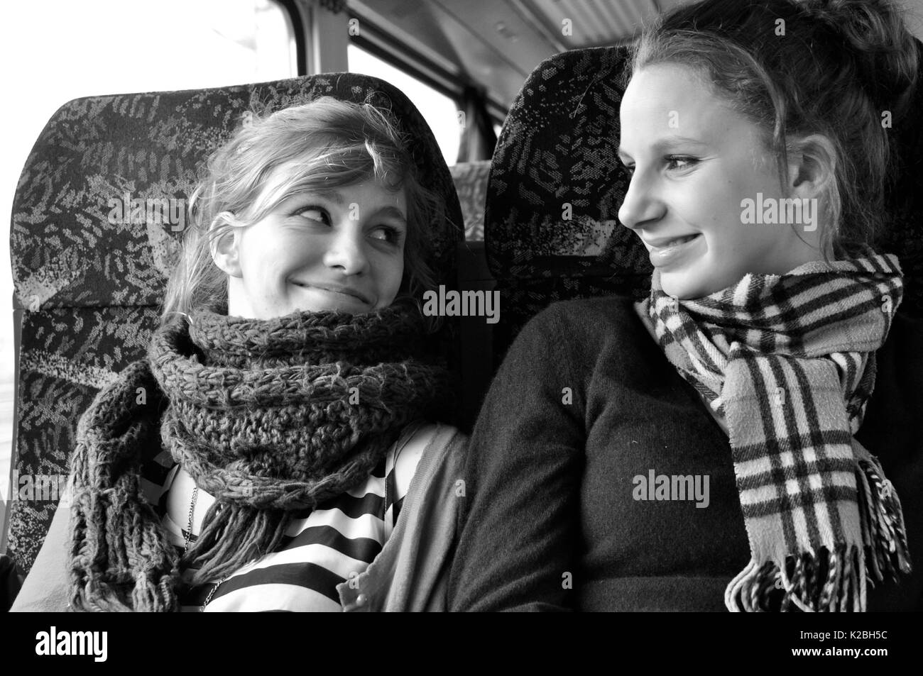 Two girls on the bus smiling at each other Stock Photo