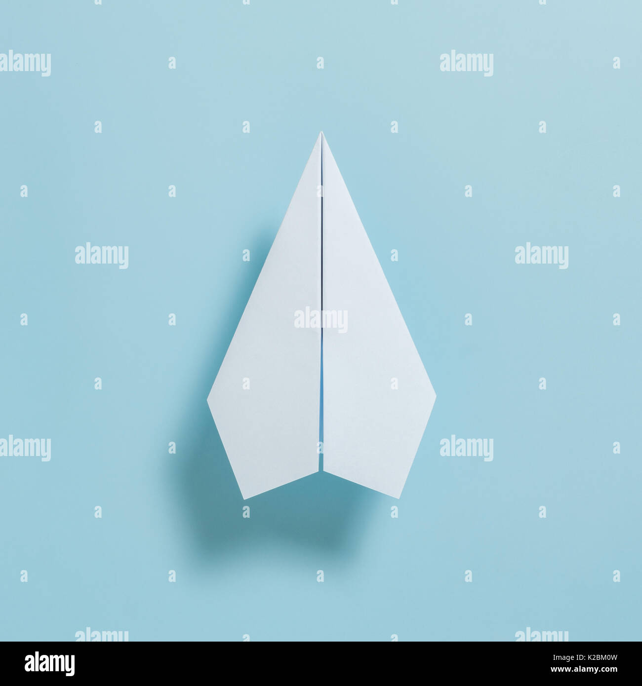 Flat lay of white paper plane on pastel blue color background Stock Photo