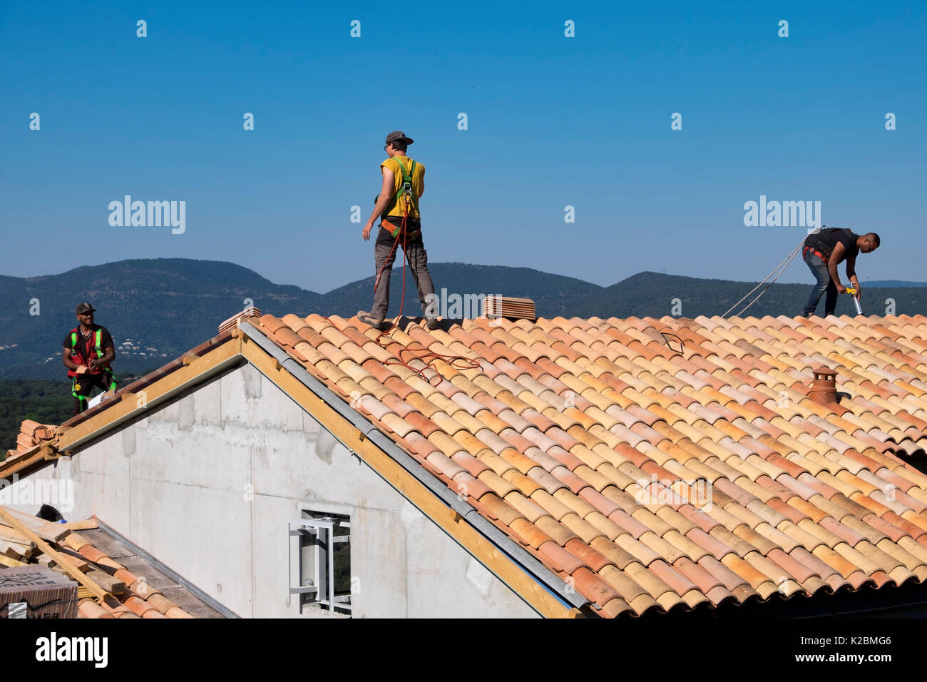 Roofers at work installing tiles on a new home in Provence, France Stock Photo