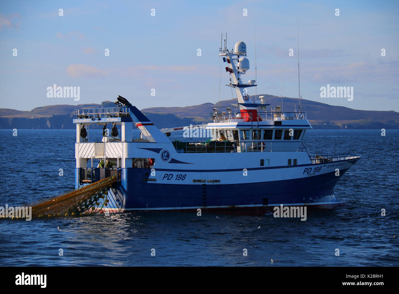 Fishing vessel 'Ocean Harvest' working in calm conditions with Fair Isle in the distance. North Sea, UK, August 2014. Property released.  All non-editorial uses must be cleared individually. Stock Photo